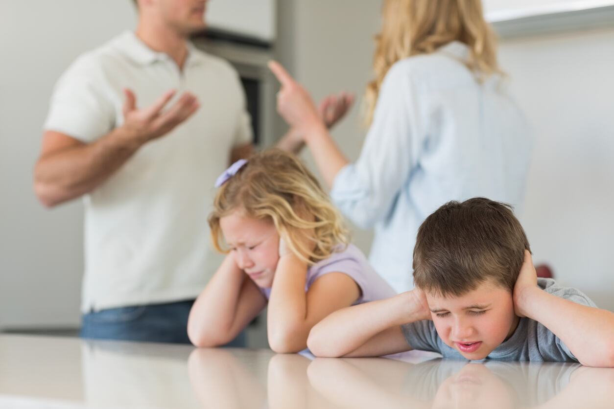 Upset children covering ears while parents argue — shows impact of domestic violence on child custody decisions in California.